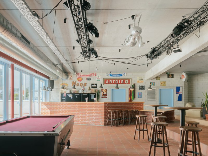 Interior bar area with terracotta floor tiles, exposed ductwork, pendant lights and a pink pool table in the foreground
