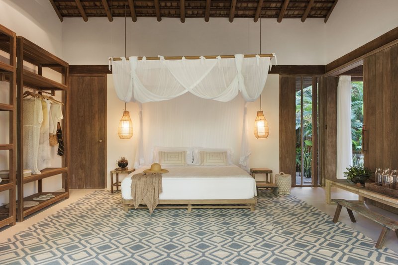 Bedroom with exposed timber ceiling, white canopy bed and patterned floor tiles beneath pendant lights