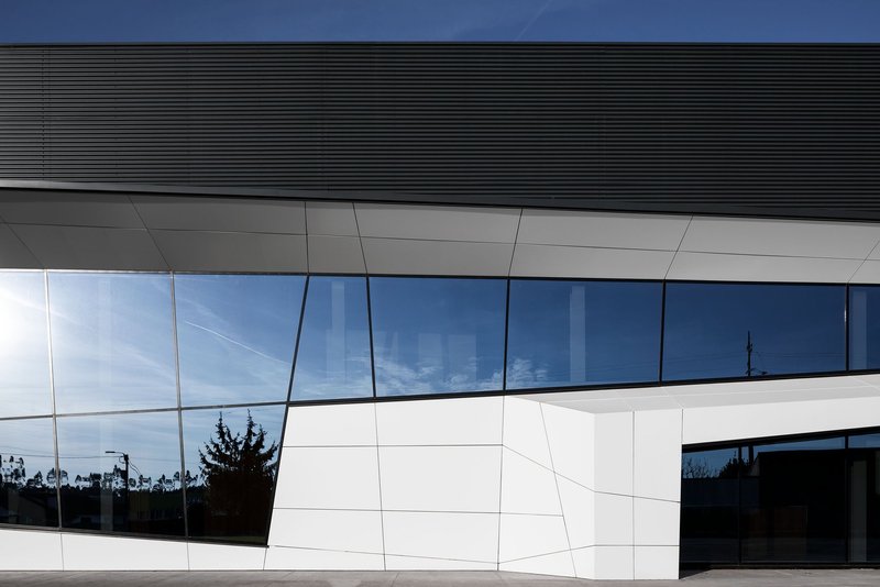Angular façade with dynamic glazing reflecting sky and surroundings.