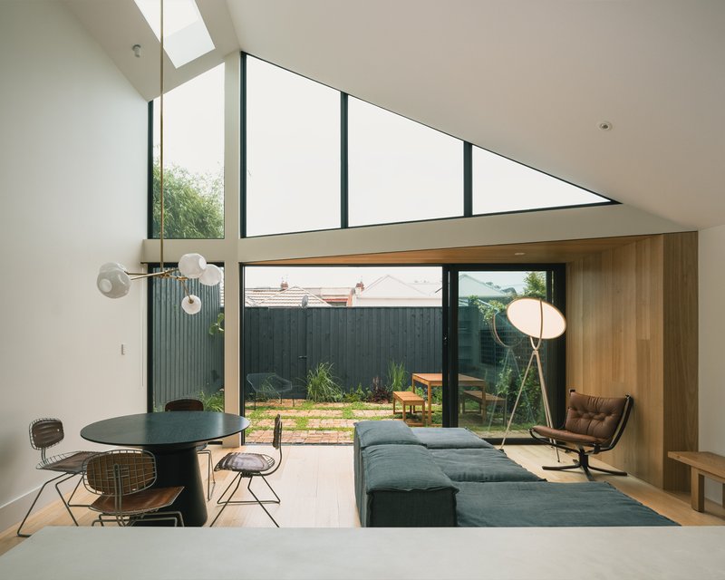 Double-height living space with clerestory windows and timber-lined bulkhead above the open-plan dining area