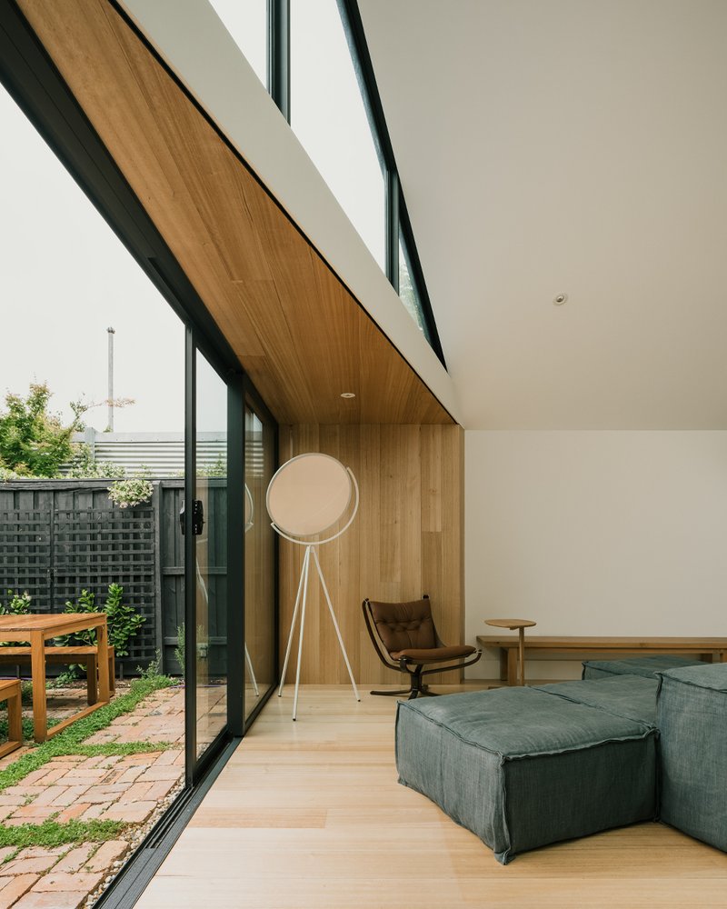 Angled timber ceiling soffit meeting floor-to-ceiling glazing along the garden-facing wall