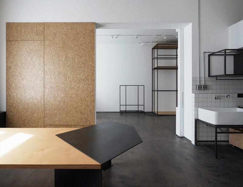 View through white doorway to open-frame metal shelving unit and sink beyond polished concrete floor