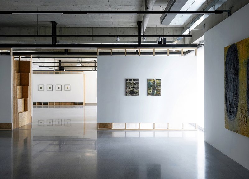 Polished concrete floor reflecting cork partitions and white walls hung with framed photographs