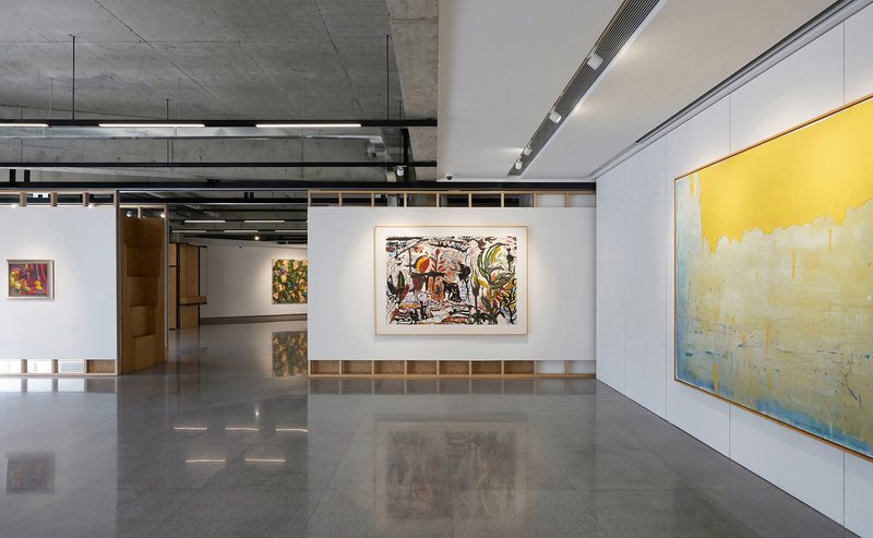 Gallery interior with reconfigurable partition walls displaying artworks under linear suspended light fixtures