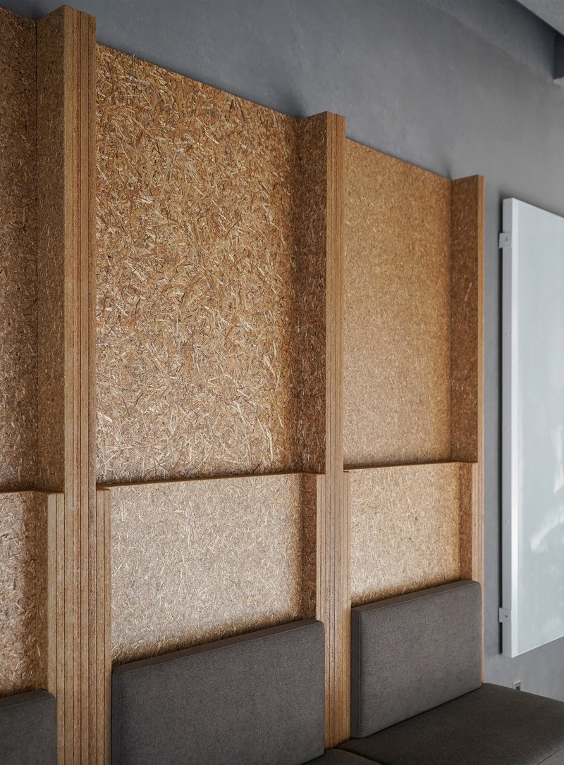 Corner wall assembly with layered cork panels framed by plywood edging and grey felt base