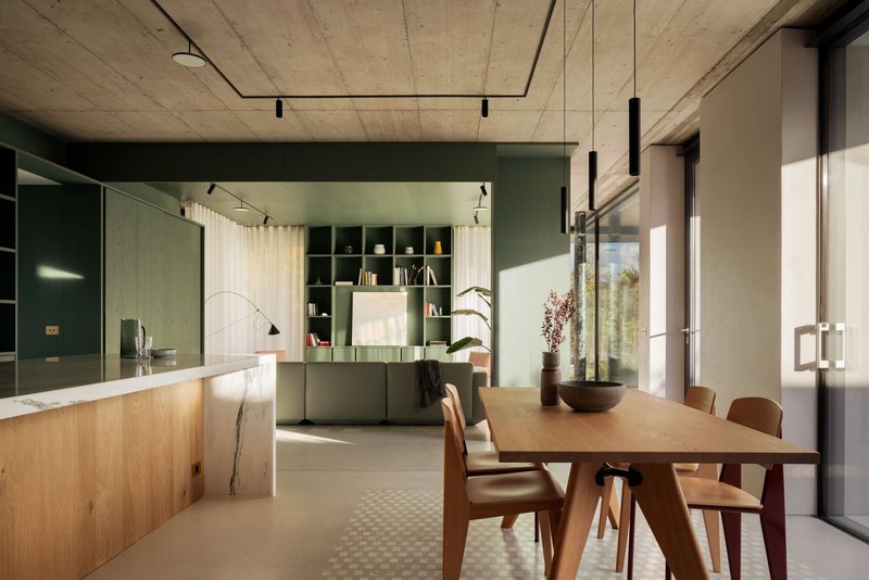 Open kitchen and dining area with exposed concrete ceiling and sage green cabinetry