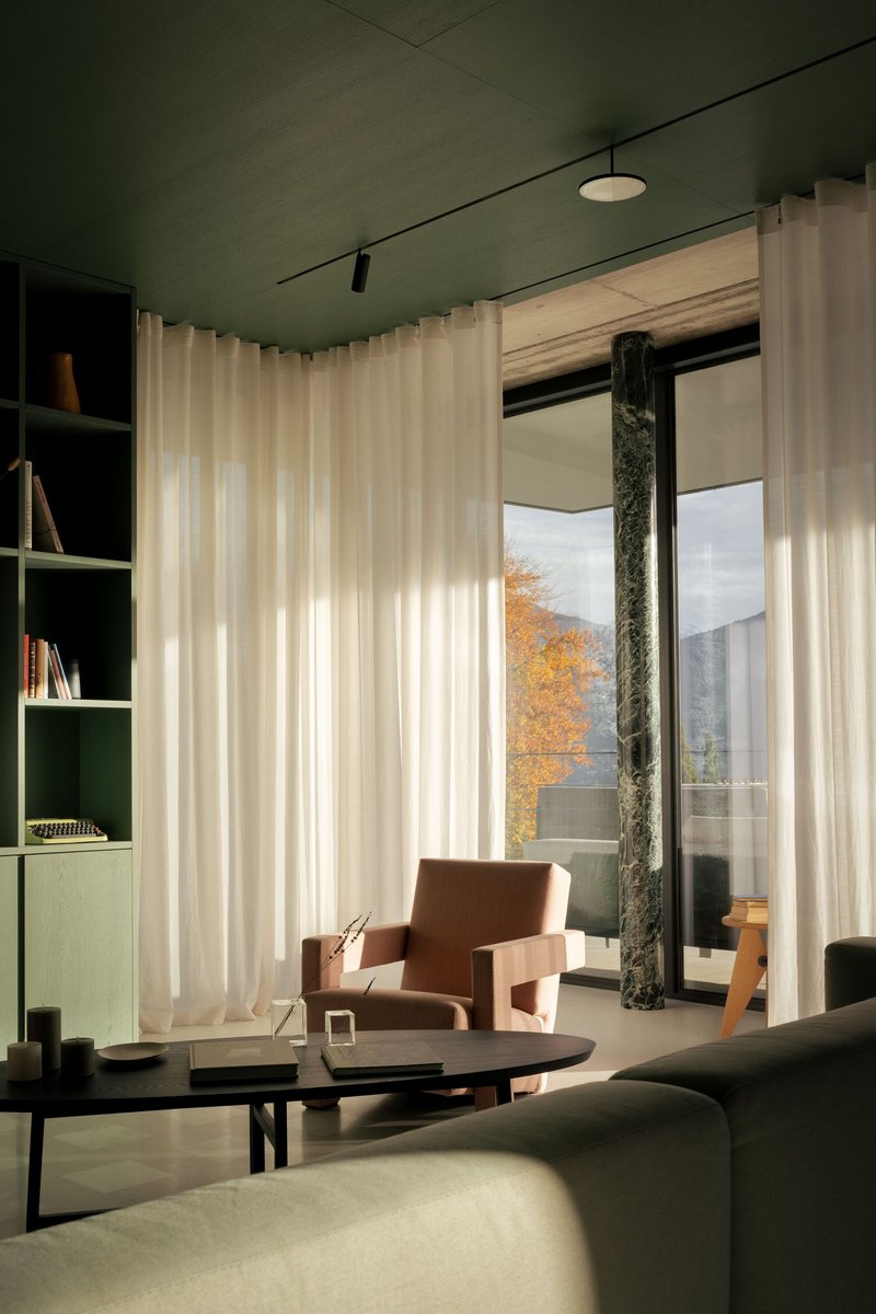 Living room with floor-to-ceiling sheer curtains framing glass doors that open to terrace with autumn trees beyond