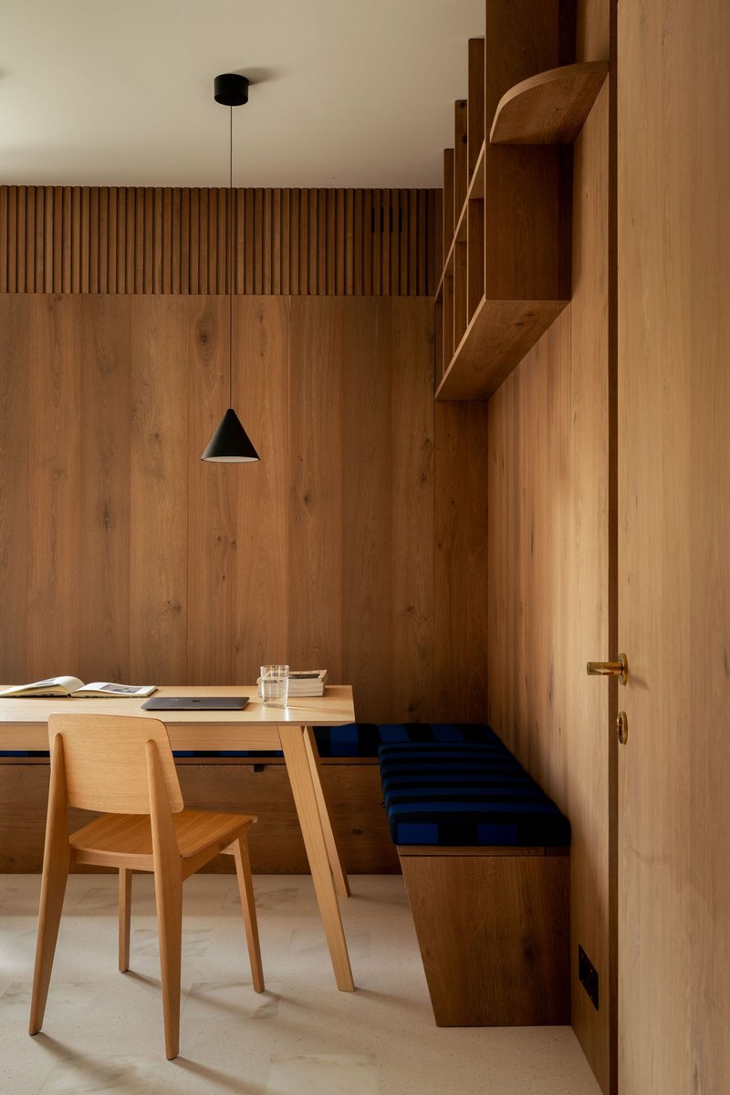Dining nook with vertical timber paneling, built-in bench with navy cushion, and suspended black pendant