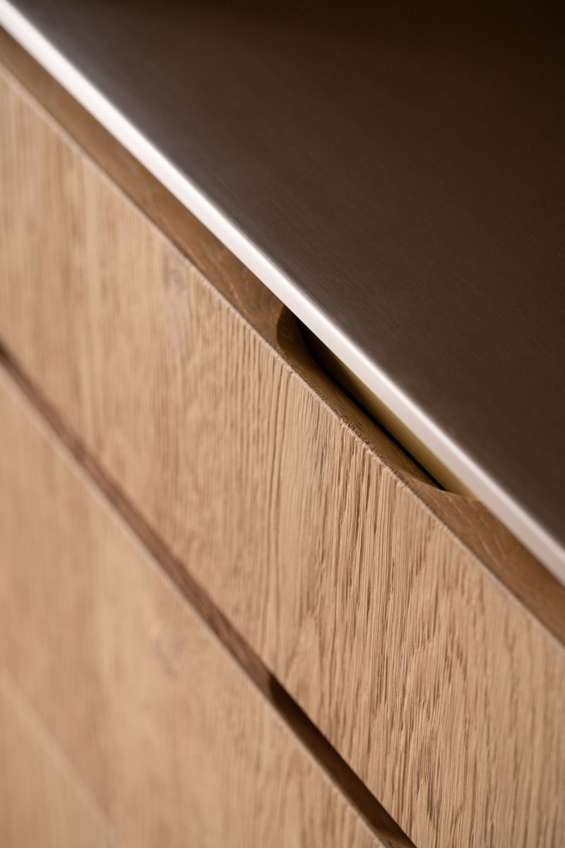 Detail of recessed finger pull in oak veneer cabinetry with integrated LED strip