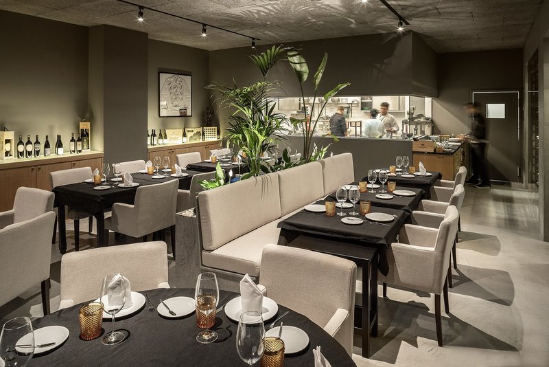 A warm contemporary dining space defined by soft lighting, neutral tones, and intimate seating clusters.