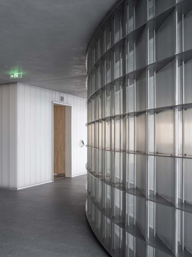 Curved translucent glass block wall adjacent to vertical ribbed panel and single wooden door