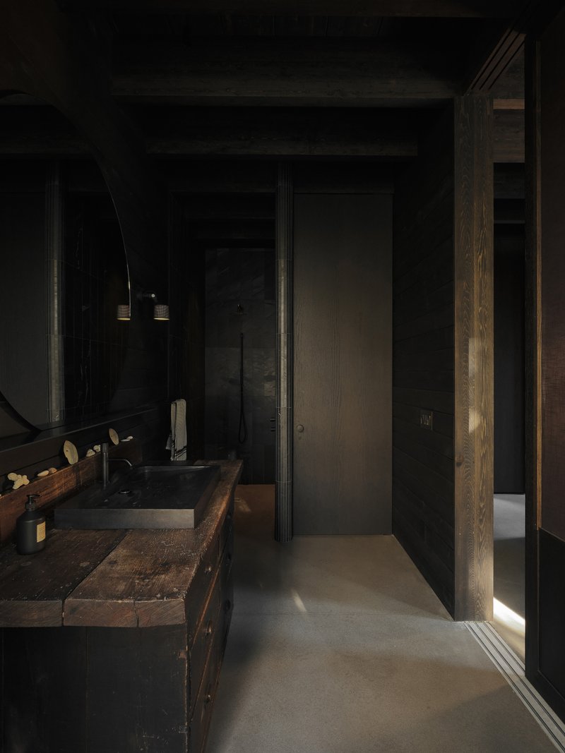 Narrow bathroom corridor with reclaimed wood vanity and vertical strip of natural light at edge