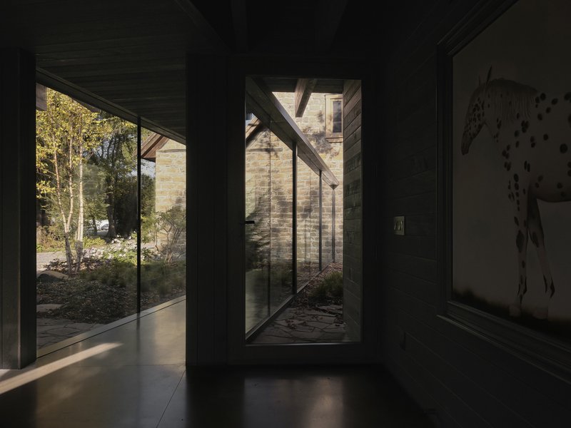 Interior hallway with tall glazed openings framing planted courtyards in afternoon light