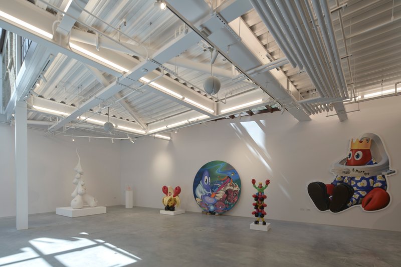 Gallery interior with exposed ceiling beams and track lighting illuminating white walls and polished concrete floor