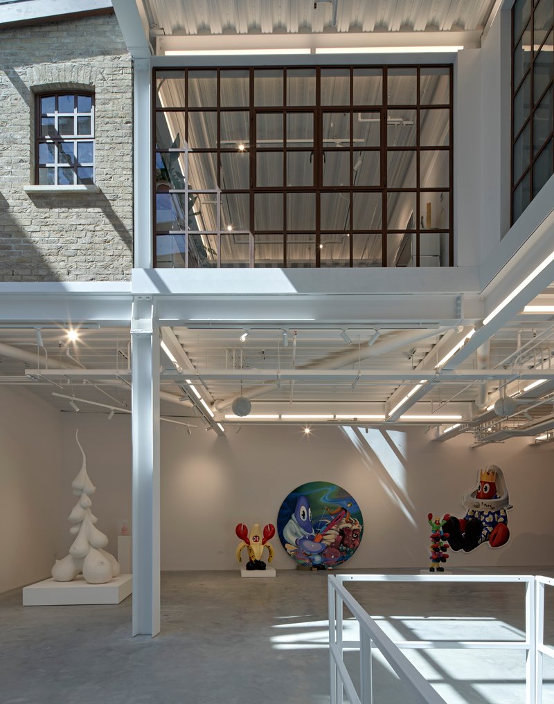 Large steel-framed clerestory window above white structural columns bringing daylight into the gallery space