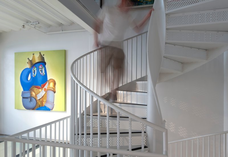 White spiral staircase with perforated metal treads and vertical bar railings with a figure in motion
