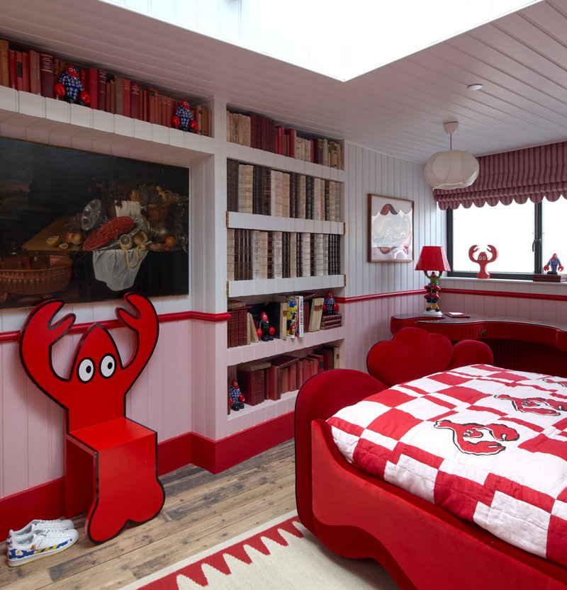 Bedroom with built-in shelving displaying books and red-themed furnishings beneath a skylight