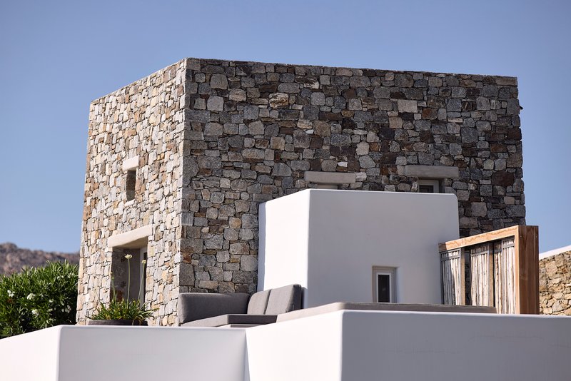 Stone masonry tower rising above white rendered volumes under a clear blue sky