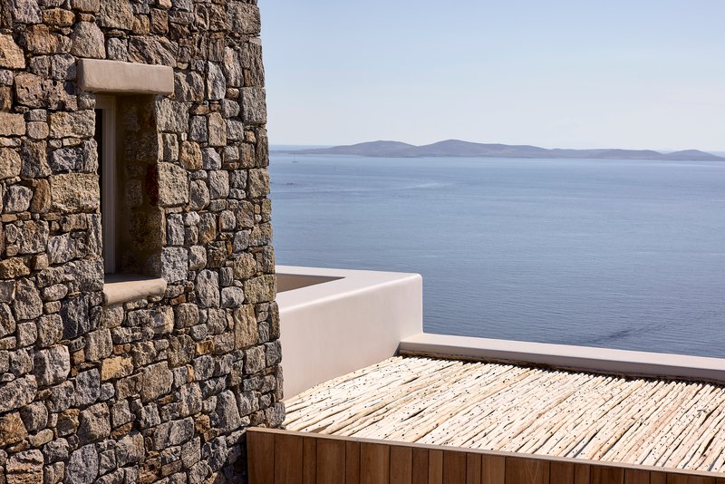Timber roof deck with stone wall opening framing distant islands across the sea