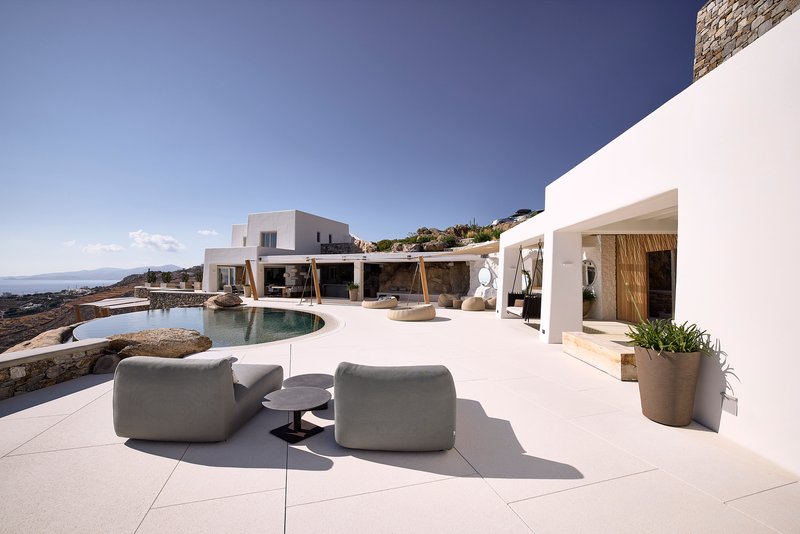 White terrace with curved pool and timber pergola overlooking the ocean
