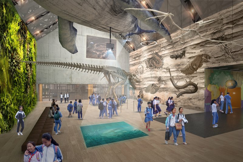 Museum hall with suspended whale skeleton and vertical green wall alongside visitors on polished floor