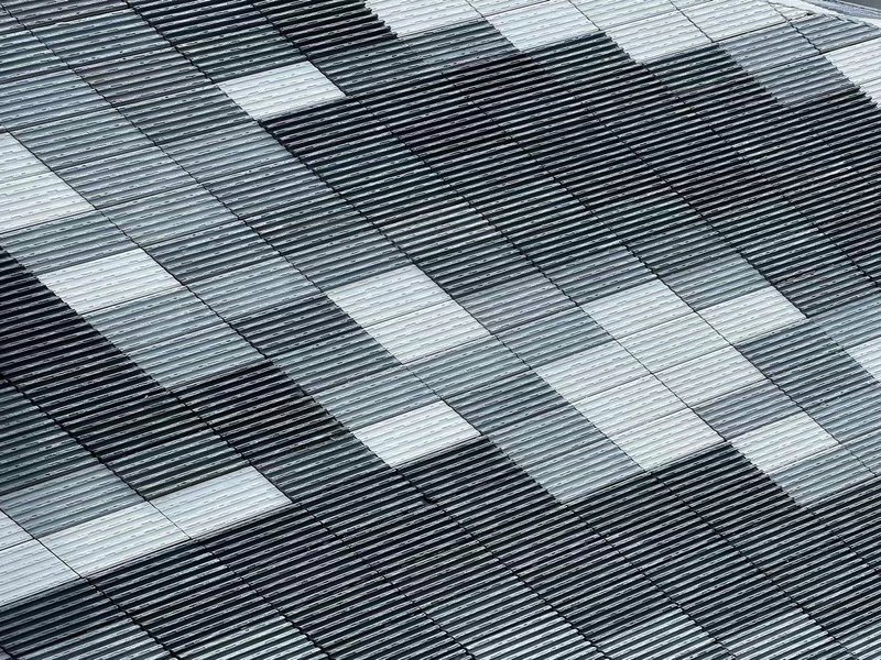 Detail of the horizontal metal louvered facade with scattered white panel openings in a pixelated pattern