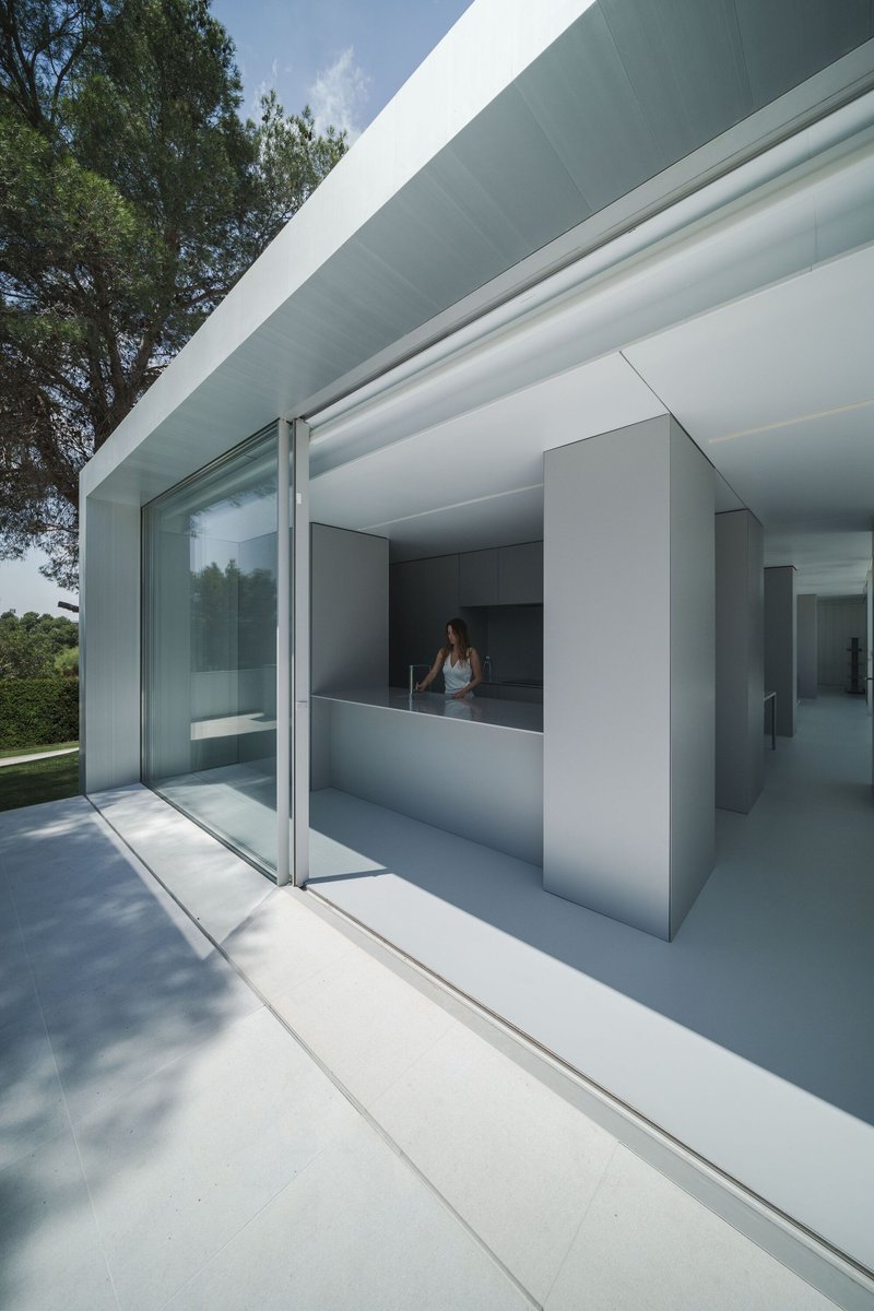Glass corner threshold with sliding panels connecting interior kitchen volume to exterior terrace