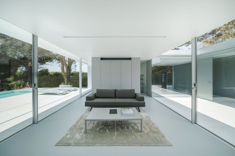 Living room with floor-to-ceiling glass walls opening to pool terrace on both sides