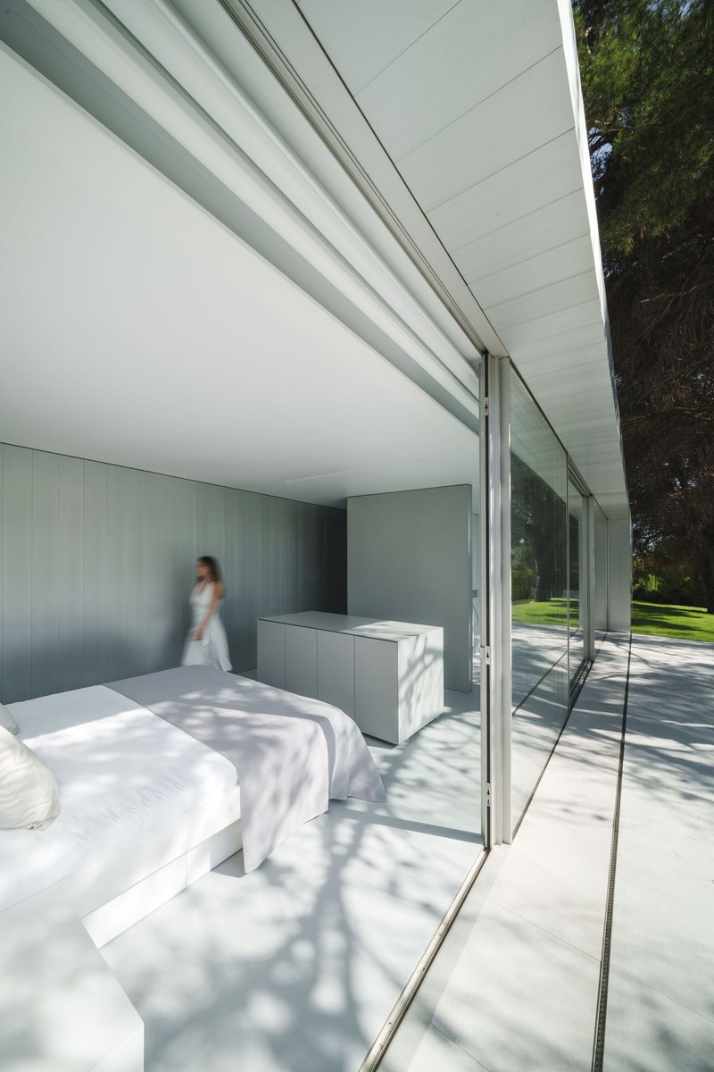Bedroom with full-height sliding glass doors opening to terrace with dappled tree shadows on floor