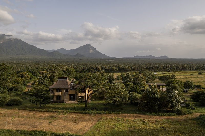 Elevated view of the residence among trees with mountain range in the distance at dusk