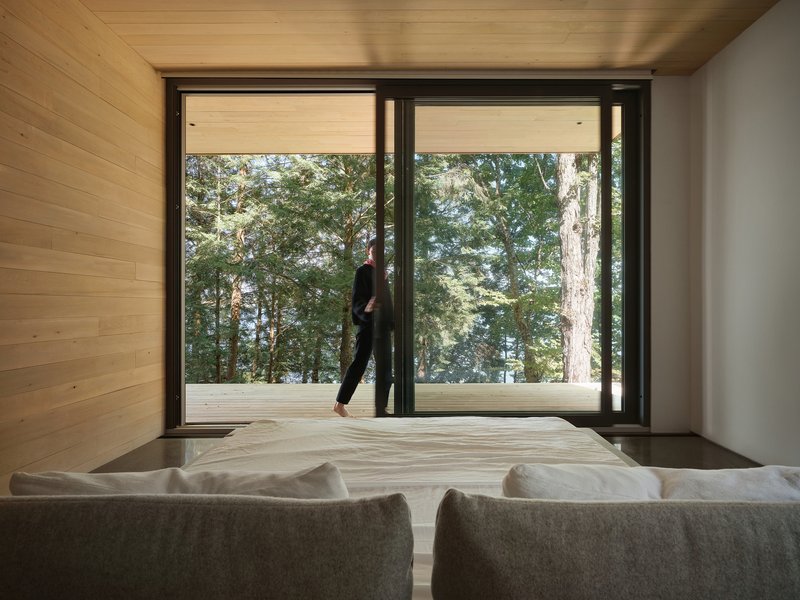 Living room with sliding glass doors opening to a deck where a person walks among the trees