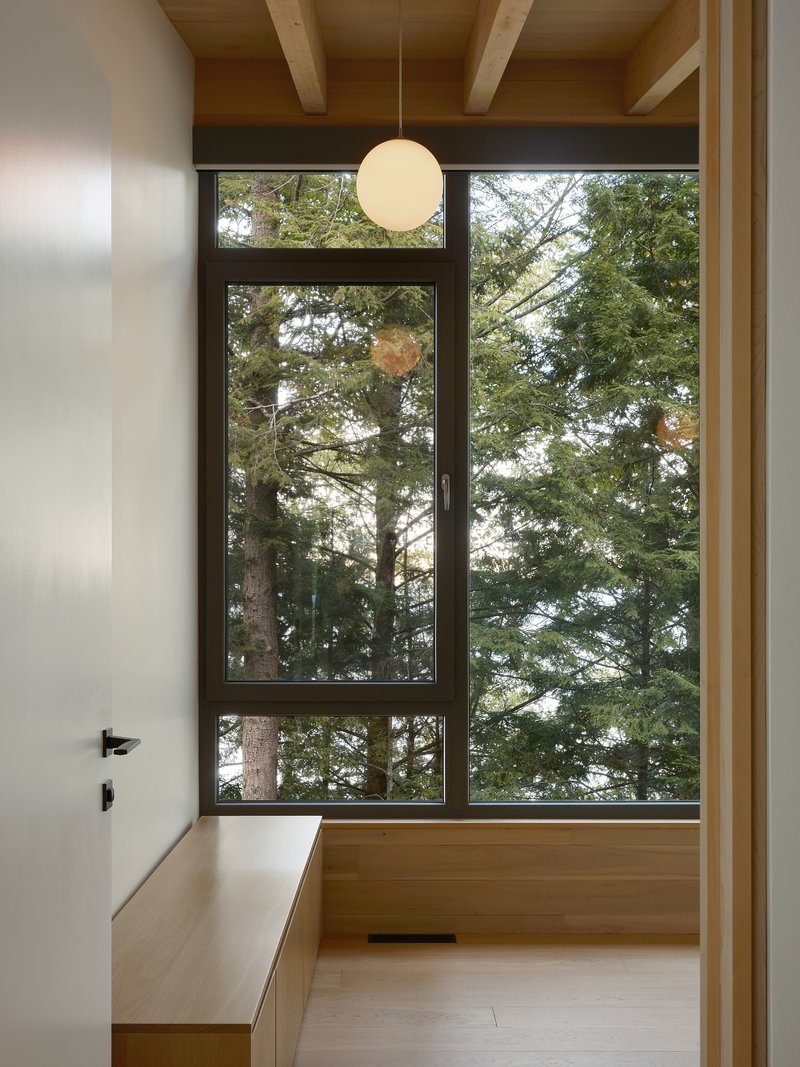 Bathroom with full-height window framing forest views and timber ceiling beams with pendant light
