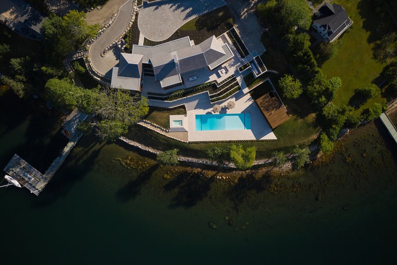 Aerial view of the residence with swimming pool and terraced retaining walls along the water's edge