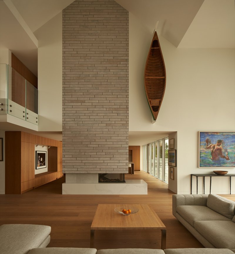 Living room with arched brick fireplace chimney and suspended wooden canoe on the wall