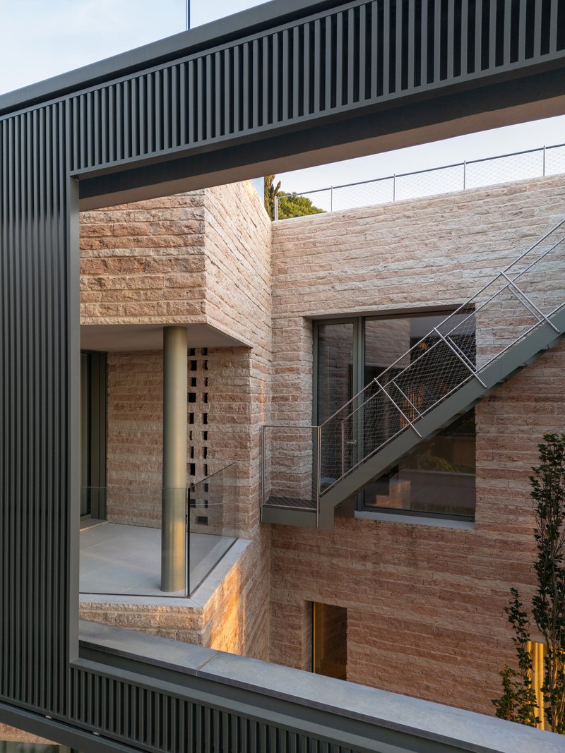 Courtyard view showing rammed earth walls, external metal stair and overhanging slatted soffit