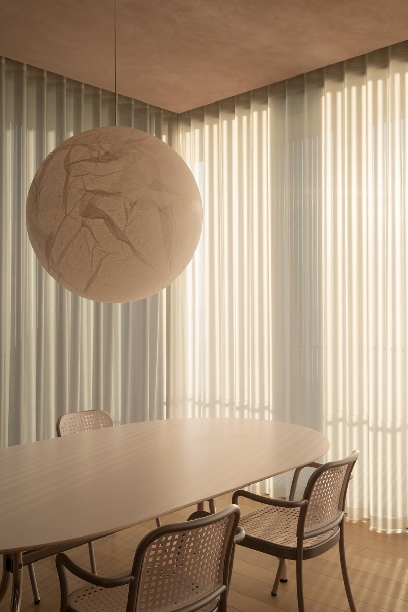 Dining area with spherical pendant light and sheer curtains filtering soft afternoon light