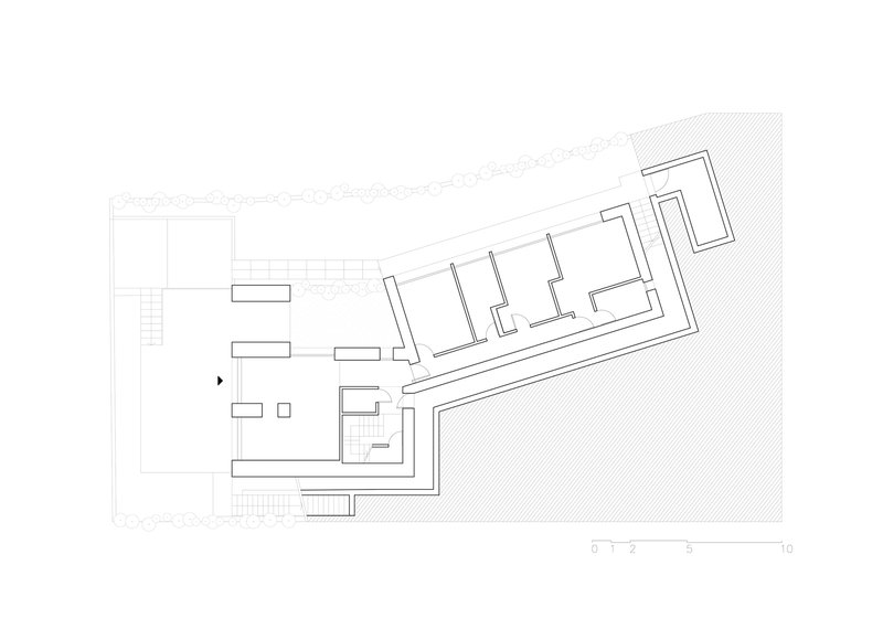Ground floor plan drawing showing two connected rectangular volumes with interior rooms and landscaped border