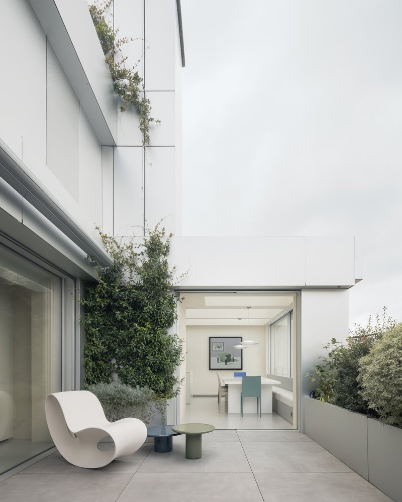 Terrace with planted beds and single chair looking through glazed doors toward the interior