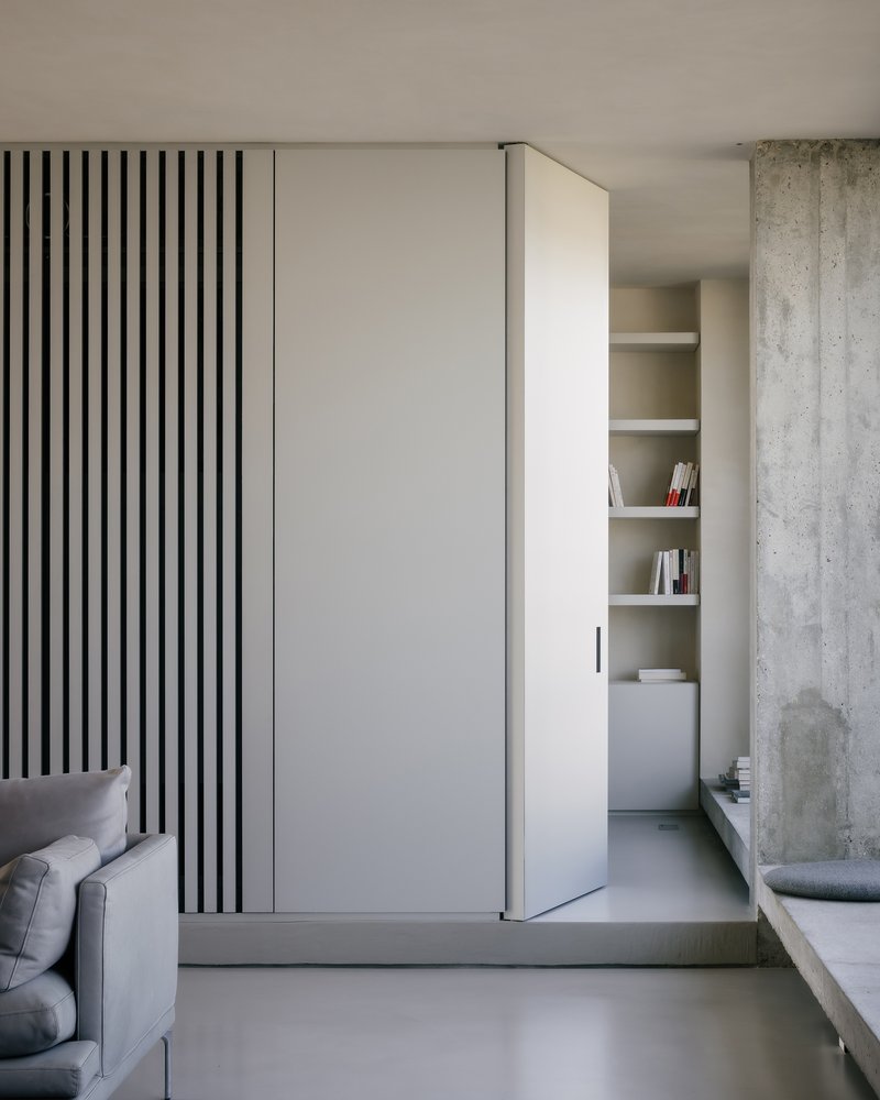 Sliding door panel with black vertical stripes adjacent to exposed concrete column and built-in shelving