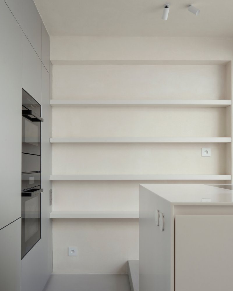 Kitchen wall with horizontal floating shelves above integrated oven cabinets