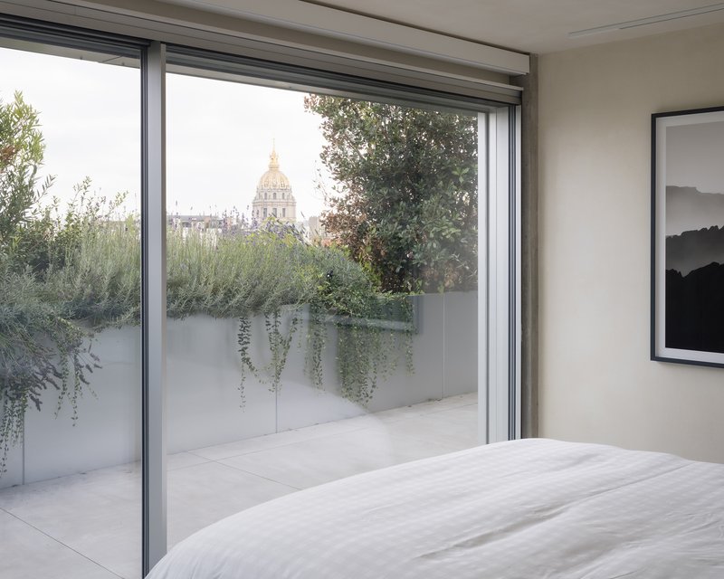Bedroom with sliding glass door opening to planted terrace with trailing vines