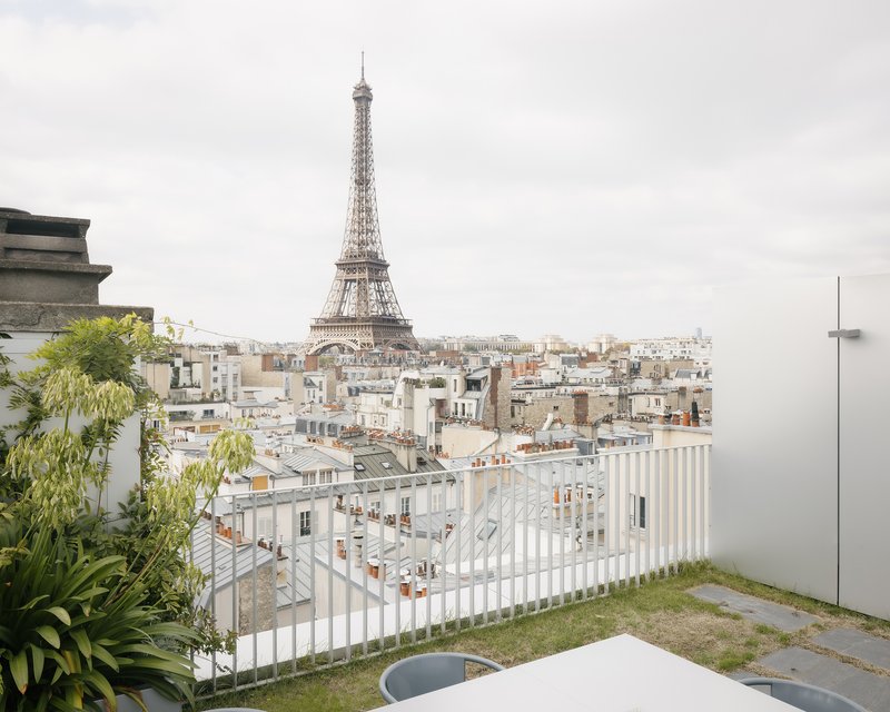 Rooftop terrace with white vertical slat railing and lawn facing the historic cityscape in morning light
