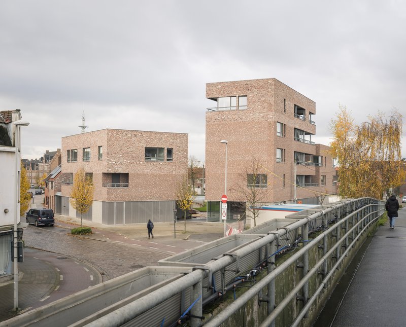 View from bridge showing brick housing blocks with ground-level glazing under overcast sky