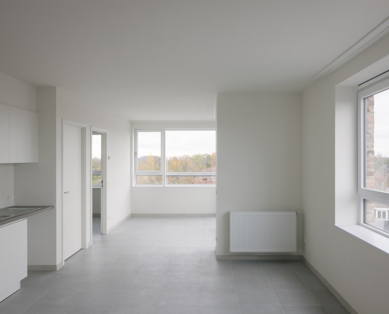 White interior room with grey tile floor and windows overlooking autumn foliage