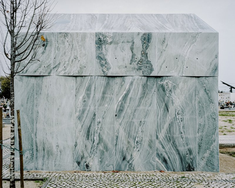 Rear elevation of the marble-clad chapel volume showing horizontal panel joints in the cemetery