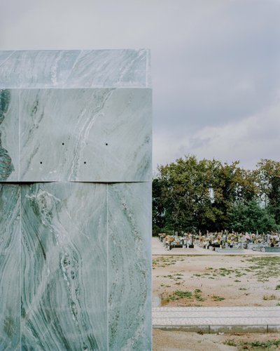 This architectural image captures a cemetery scene, juxtaposing a green marble structure with rows o