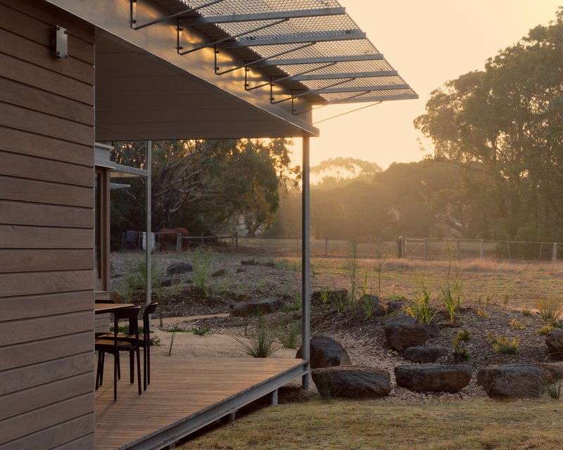 Timber deck with metal pergola and planted rock garden at golden hour