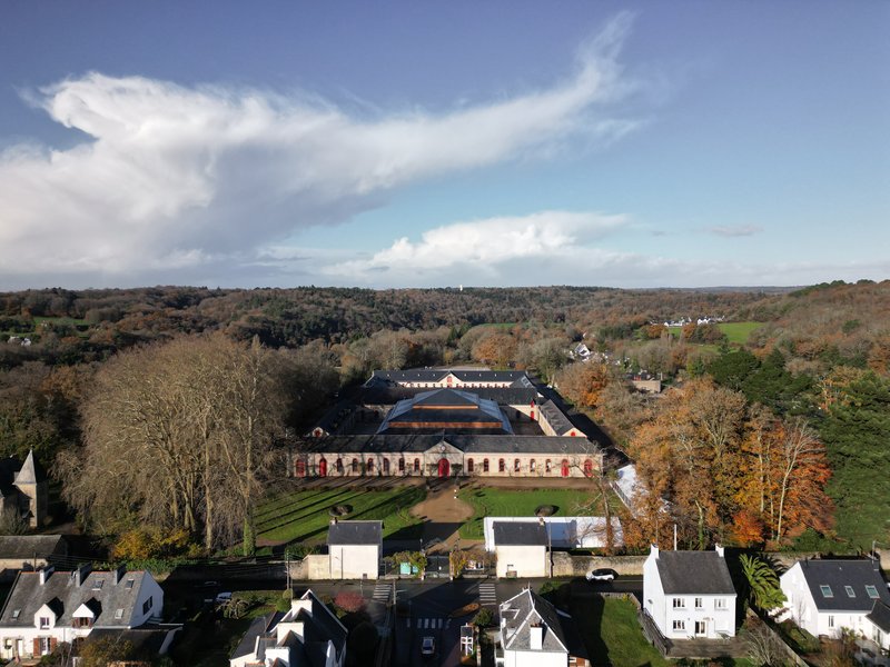 Aerial view showing the tiered roof and symmetrical courtyard surrounded by autumn trees and countryside