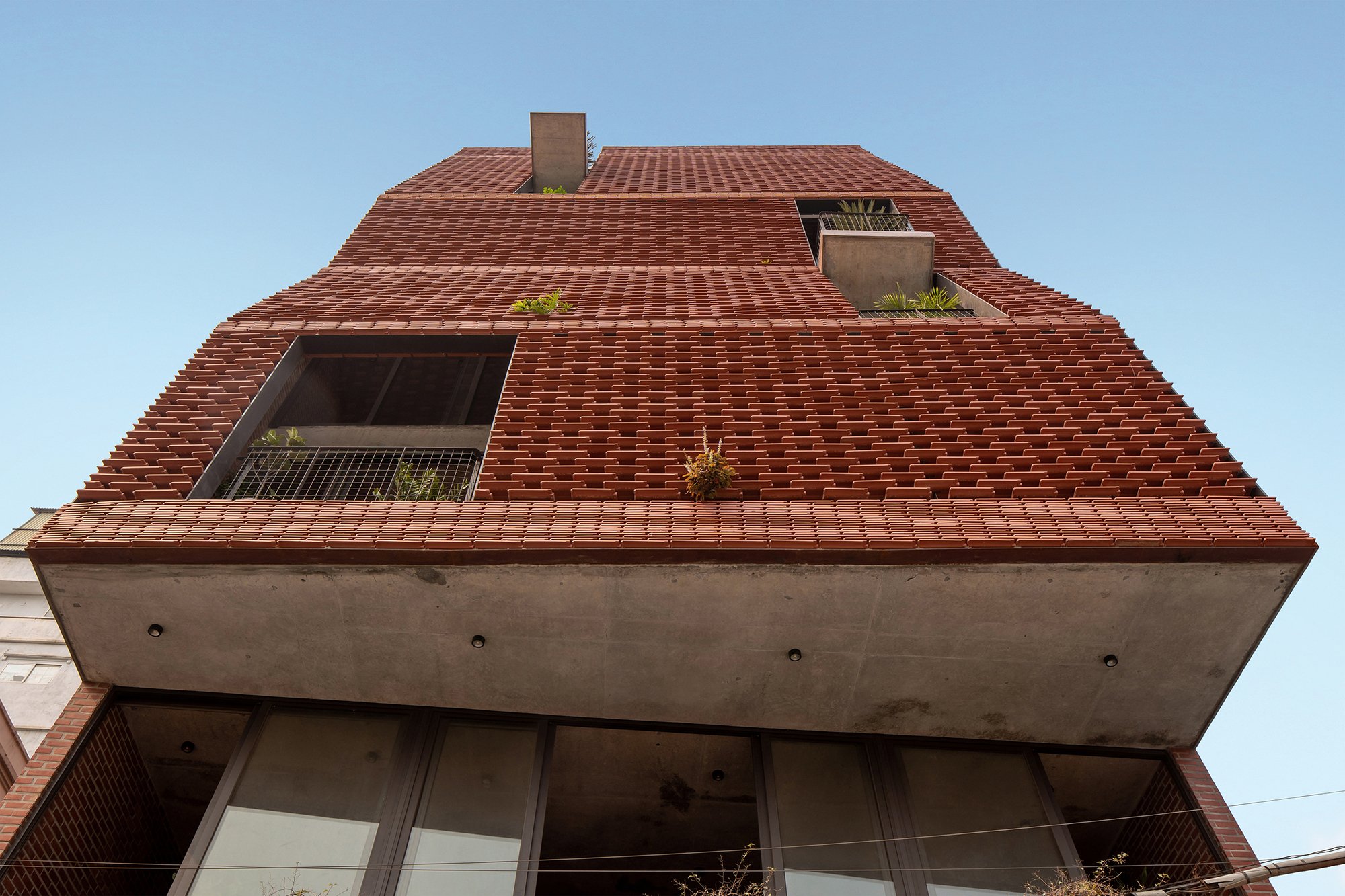 H&P Architects Stack a Vertical River of Brick and Greenery in Hanoi