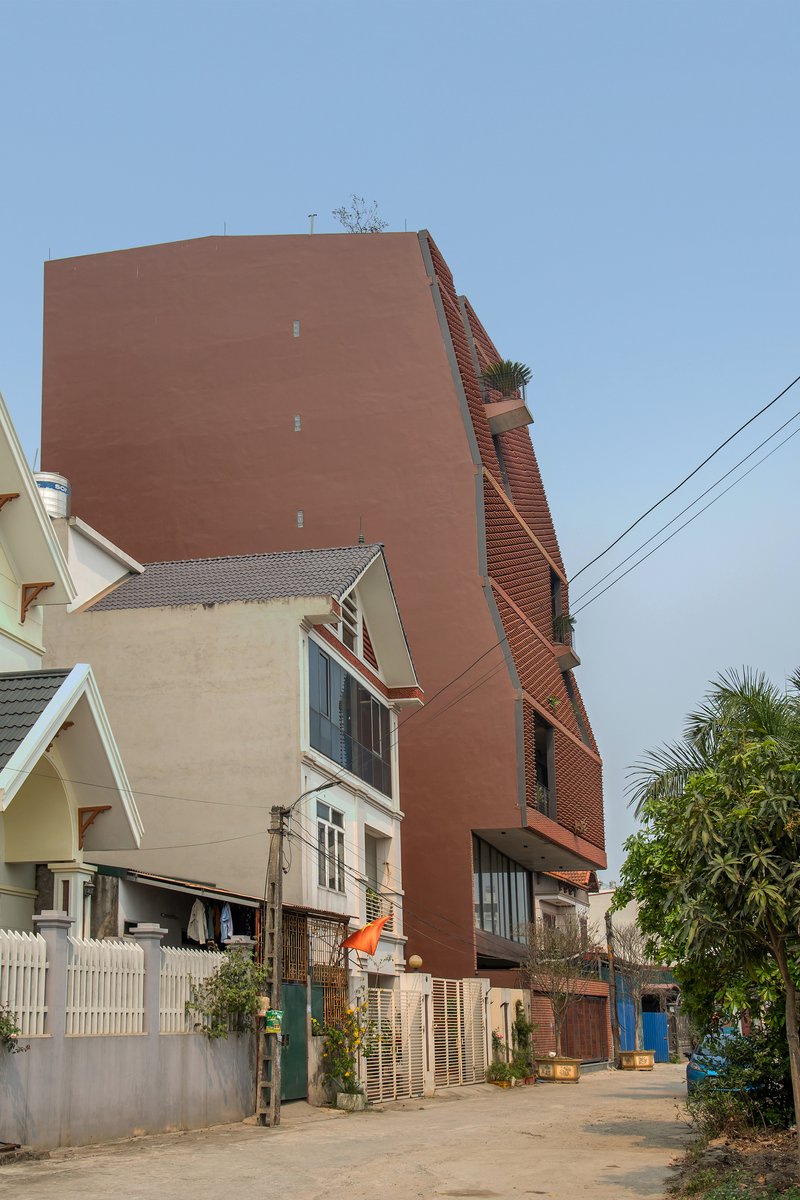Terracotta brick tower rising above low residential houses along a narrow street with overhead power lines
